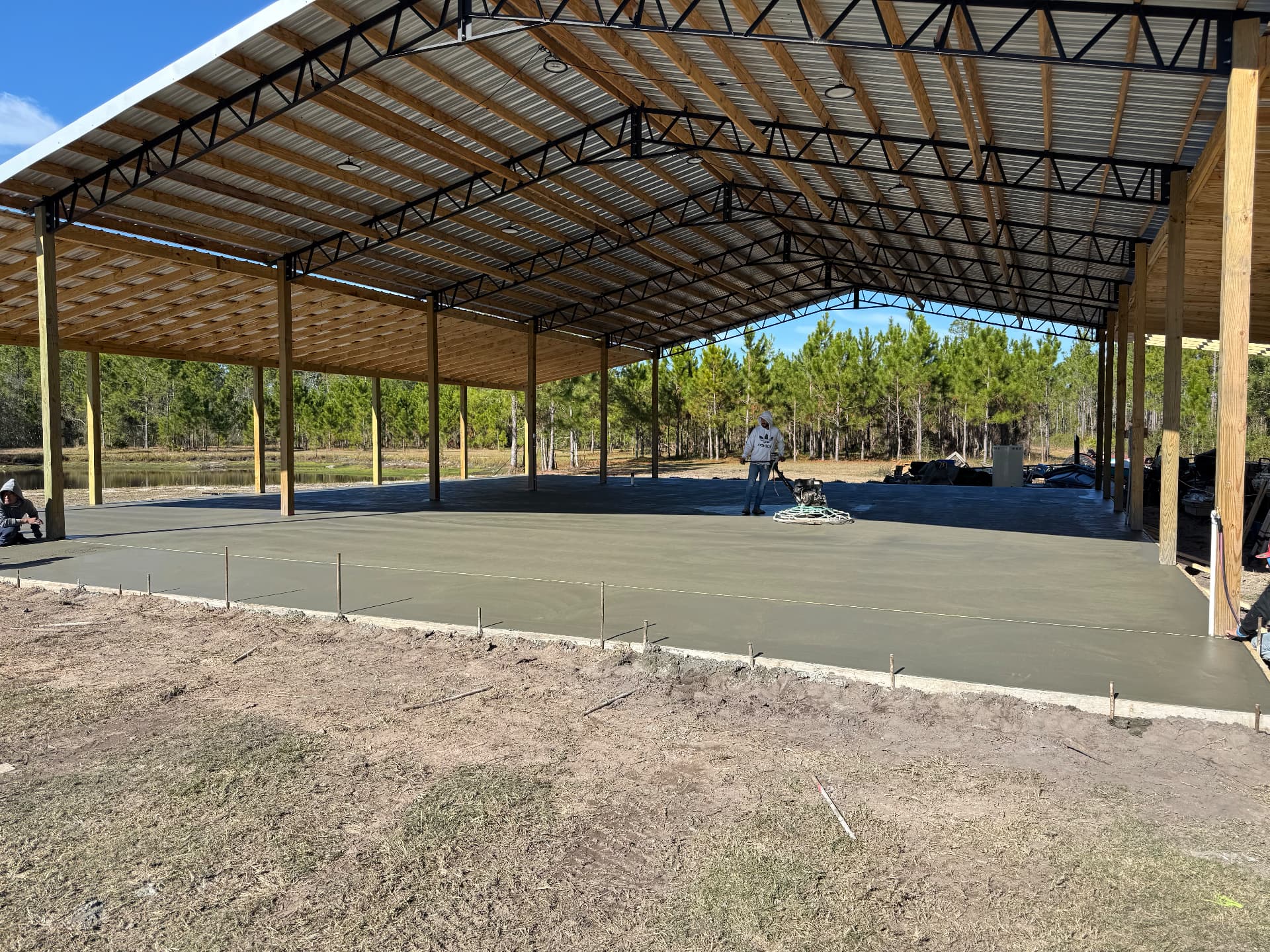 Freshly finished concrete slab poured under a large pole barn